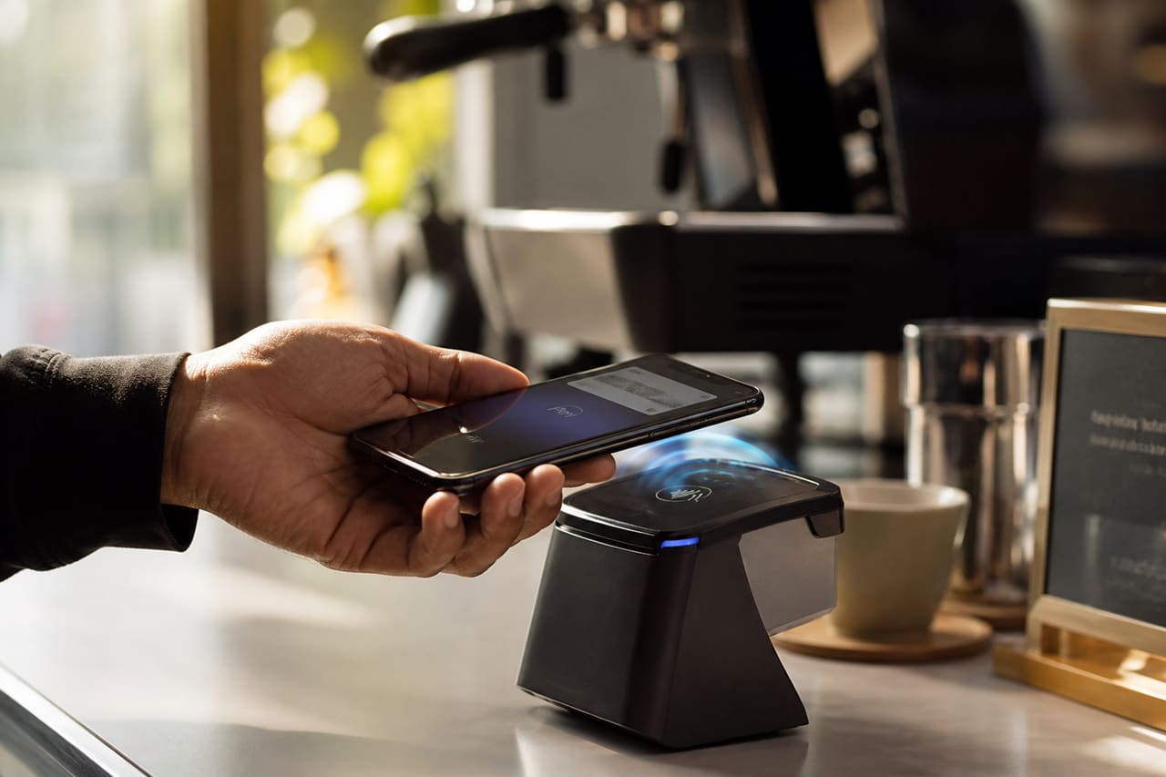 Person Using Smartphone for Contactless Payment at Cafe Terminal
