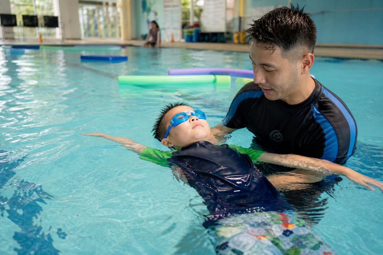 Swim Instructor Teaching a Child in an Indoor Pool