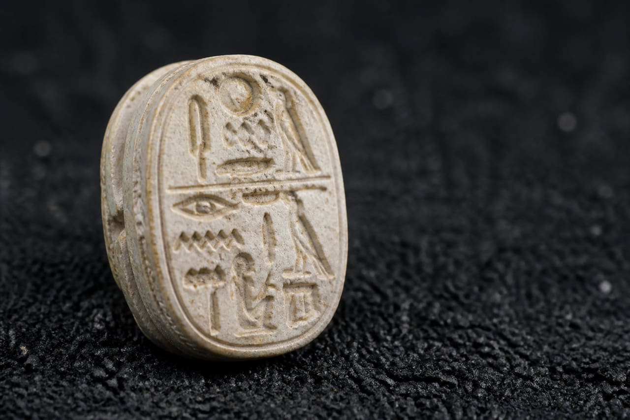 Ancient Egyptian Steatite Scarab Amulet on Dark Sand