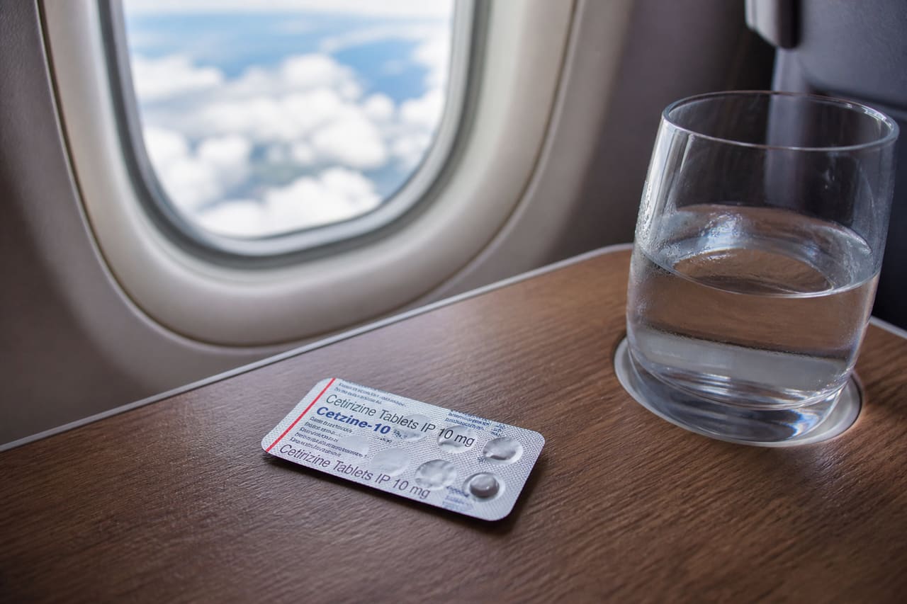 Cetirizine Tablets and Water on an Airplane Tray Table