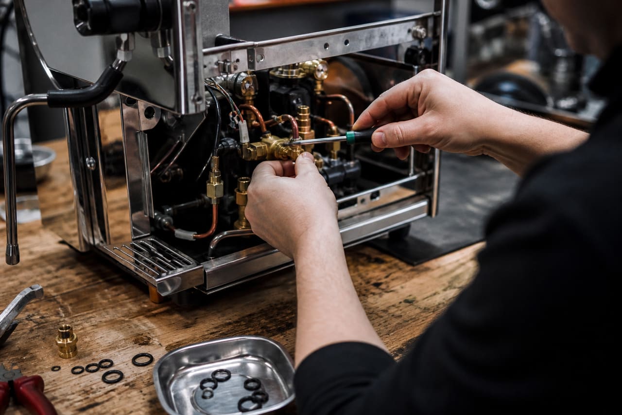 Technician Repairing an Espresso Machine in a Professional Workshop