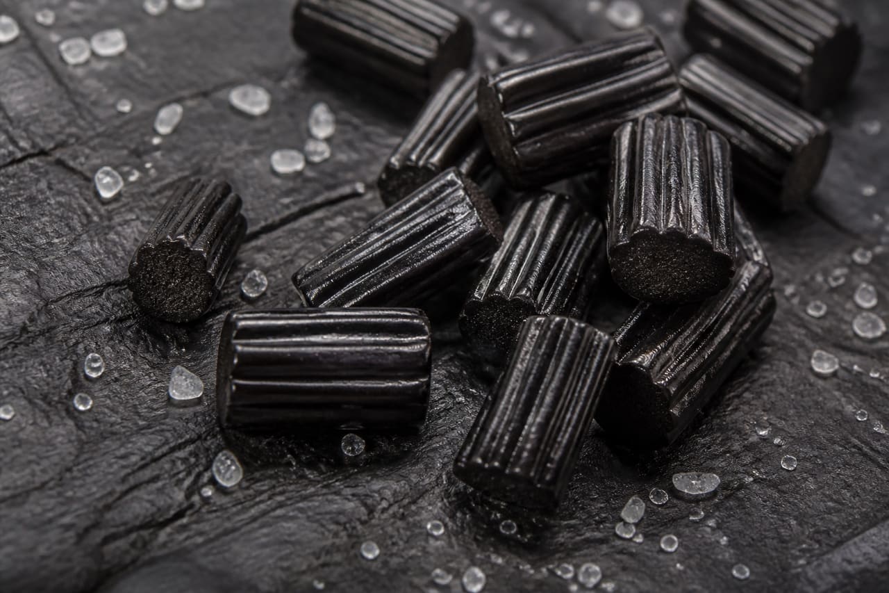 Black Salt Licorice Candy Pieces on a Dark Slate Surface