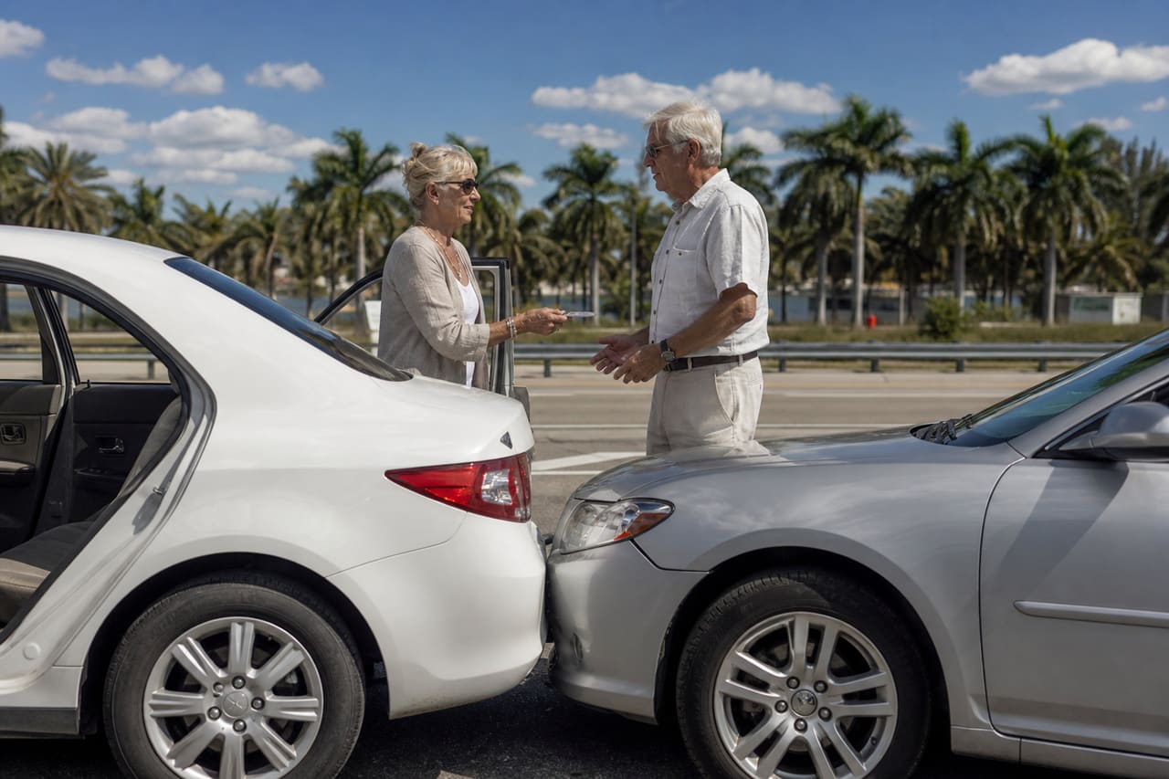 Elderly Couple Exchanging Insurance After Minor Car Collision