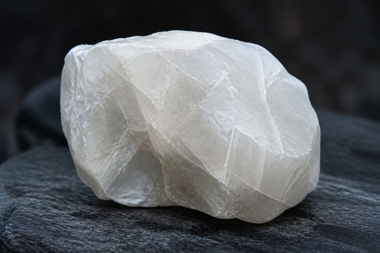 Raw Alabaster Mineral Specimen on Dark Slate Surface