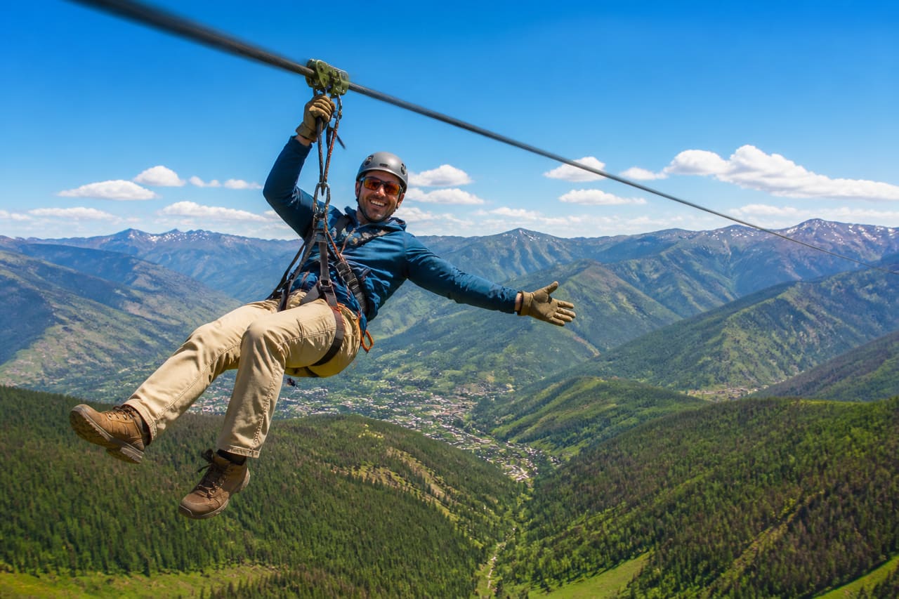 Adventurer Ziplining Over a Lush Valley in Vail