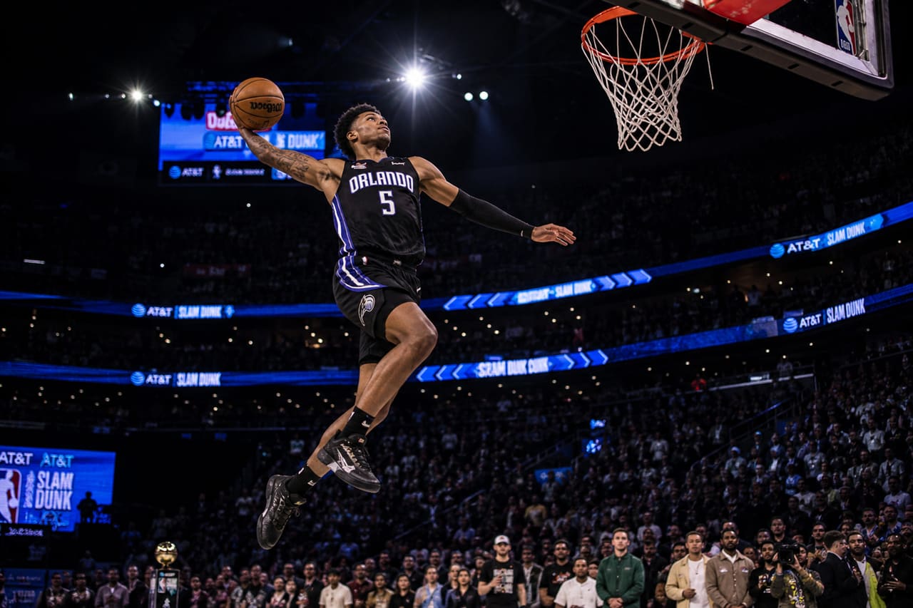 Professional Basketball Player Performing a Slam Dunk in an Arena