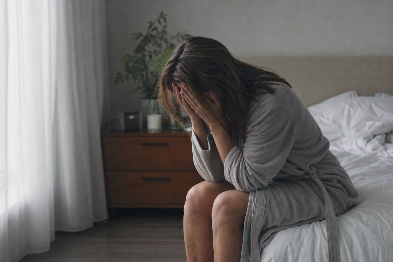 Woman Sitting Alone on Bed Looking Distressed