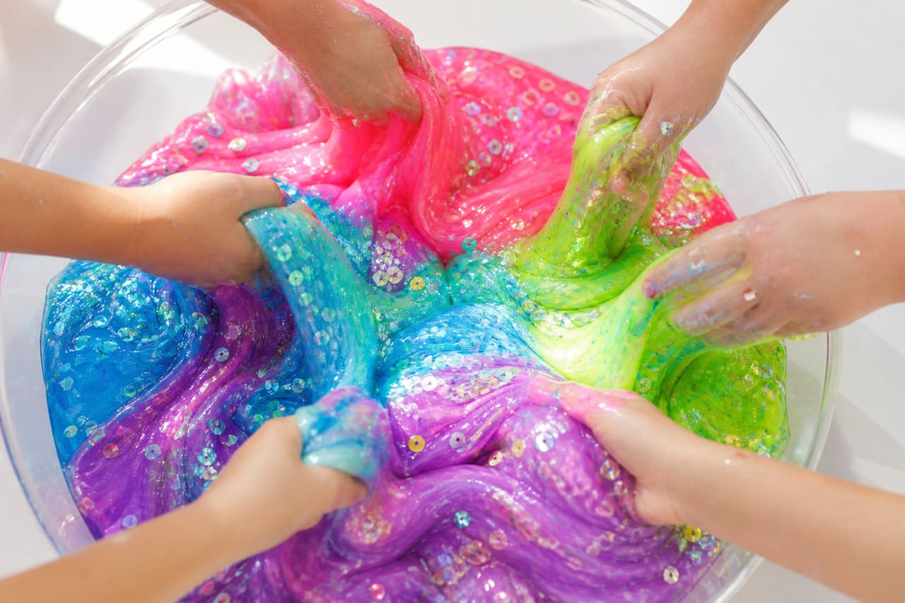 Hands Mixing Colorful Giant Slimes in a Clear Basin